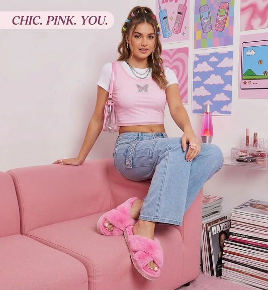 Woman sitting on a pink couch in a room with pink decor and magazines.
