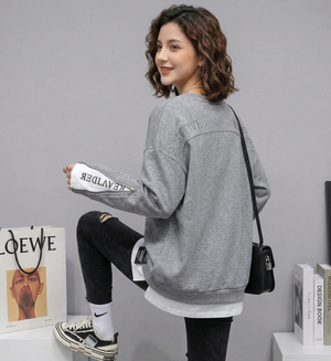 Woman wearing a gray oversized sweatshirt with a plain background