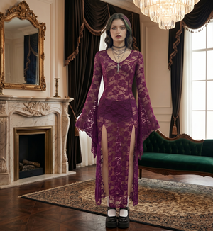 Woman in a purple lace dress standing in an elegant room with a fireplace and green sofa.