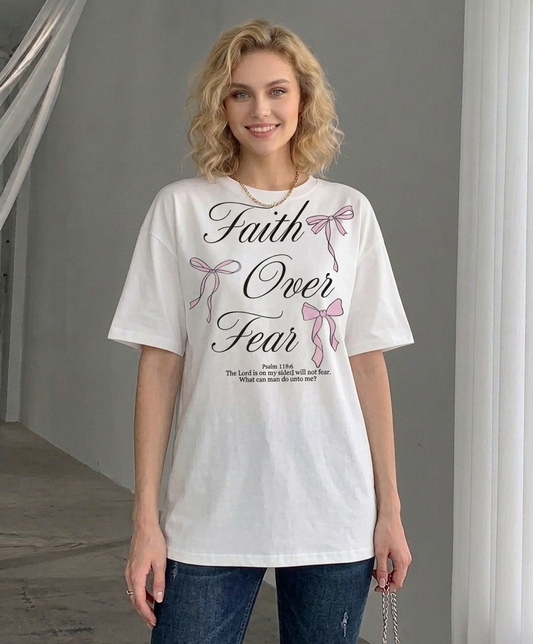 Woman wearing a white t-shirt with 'Faith Over Fear' text and pink ribbons.