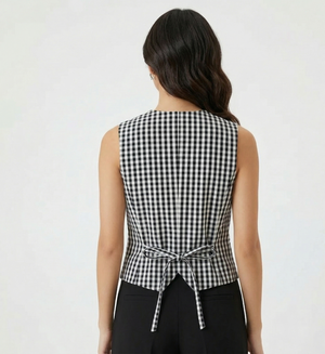 Woman wearing a black and white checkered sleeveless top with a tie waist on a white background
