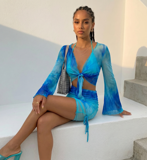 Woman in a blue dress sitting on white steps with a neutral background