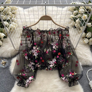 Black floral embroidered shorts on a hanger with a white floral background