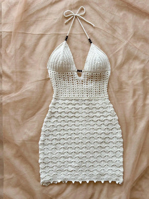 White crochet dress hanging on a beige bedspread