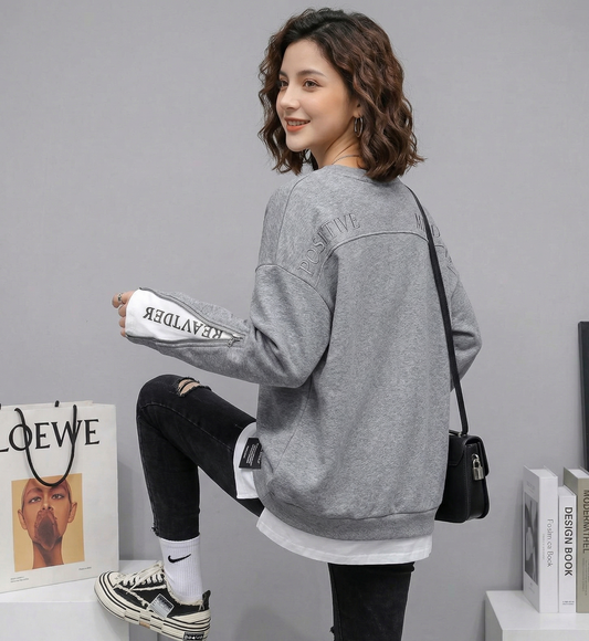 Woman wearing a gray oversized sweatshirt with a plain background