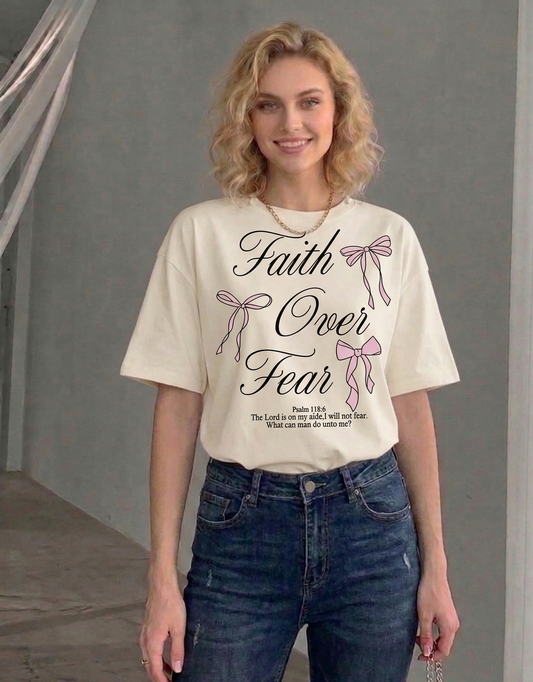 Woman wearing a t-shirt with 'Faith Over Fear' text and ribbons design.
