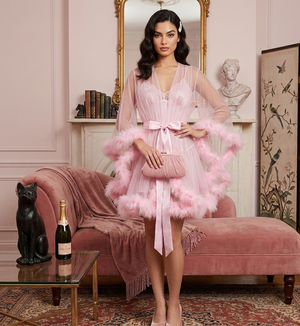 Woman in a pink dress with feathered sleeves standing in an elegant room.