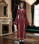Woman in a burgundy lace dress standing in an elegant room with a fireplace and chandelier.