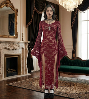 Woman in a burgundy lace dress standing in an elegant room with a fireplace and chandelier.
